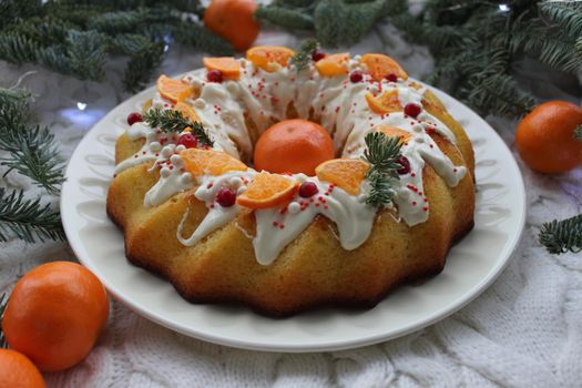 Christmas round shaped dessert is decorated with tangerine slices and coniferous twigs
