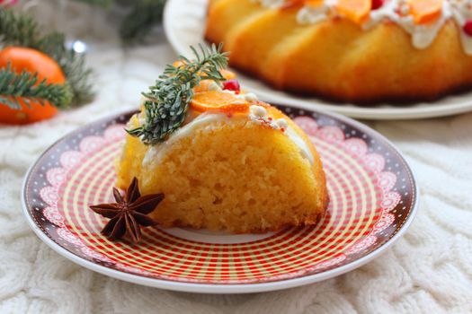 A piece of Christmas cake on the table decorated with tangerine slices and a fir branch