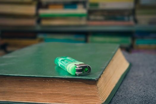 A closed book on which a lighter lies in the library, as a symbol that it is time to take a smoke break