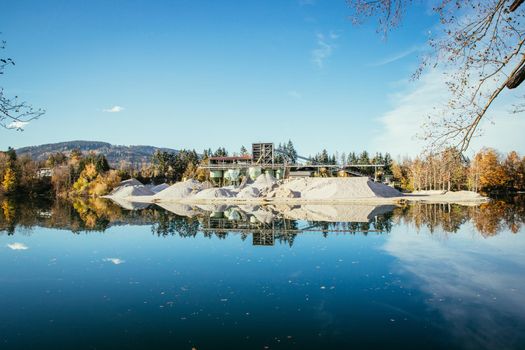 Blue lake in front of a gravel quarry, autumn time