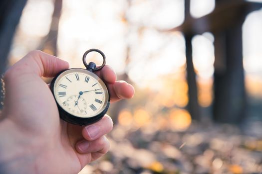 Hand held stop watch outdoors, autumn, blurry background