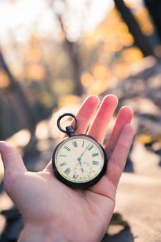 Hand held stop watch outdoors, autumn, blurry background