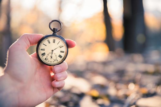 Hand held stop watch outdoors, autumn, blurry background