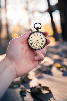 Hand held stop watch outdoors, autumn, blurry background