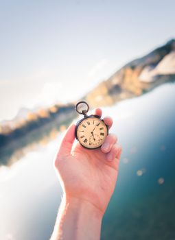 Hand held stop watch outdoors, autumn, blurry blue lake in the background