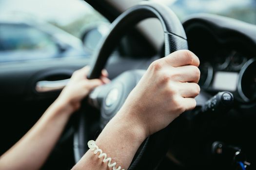 Female hands on a sports car steering wheel, car interior