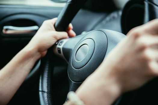 Female hands on a sports car steering wheel, car interior