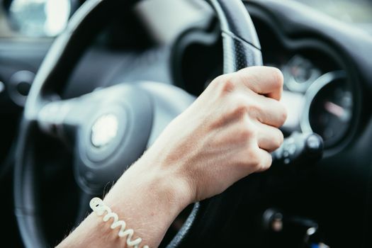 Female hands on a sports car steering wheel, car interior