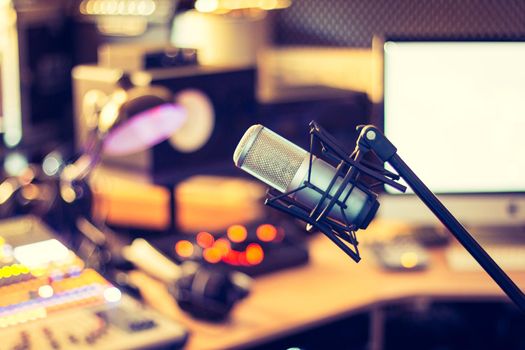 Microphone in a professional recording or radio studio, equipment in the blurry background