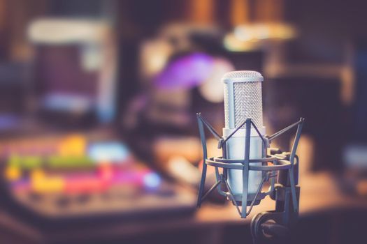 Microphone in a professional recording or radio studio, equipment in the blurry background