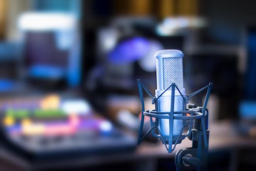 Microphone in a professional recording or radio studio, equipment in the blurry background