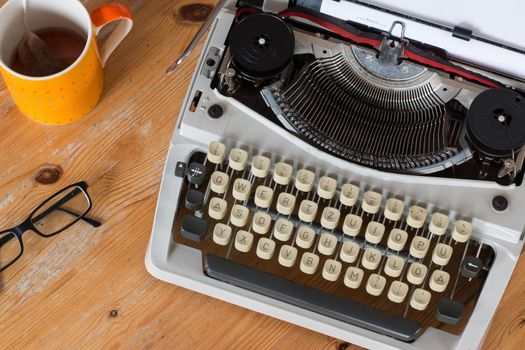 Vintage typewriter, glasses and cup of coffee on a wood desk