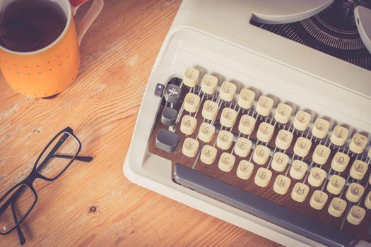 Vintage typewriter, glasses and cup of coffee on a wood desk