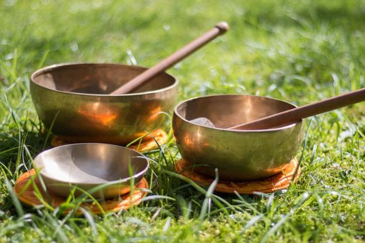 Set of metal singing bowls in the grass of the own garden, zen