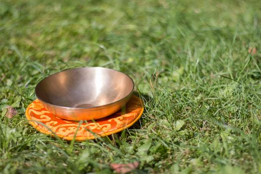 Metal singing bowls in the grass of the own garden, zen