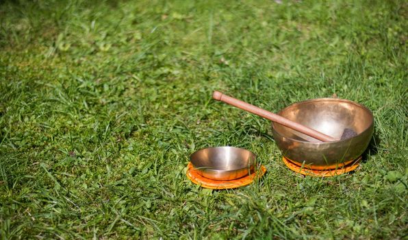 Set of metal singing bowls in the grass of the own garden, zen