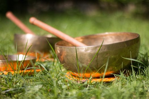 Set of metal singing bowls in the grass of the own garden, zen