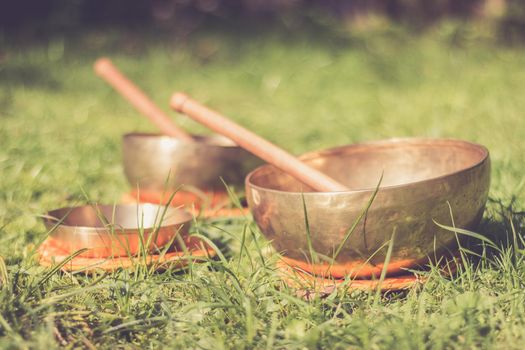 Set of metal singing bowls in the grass of the own garden, zen