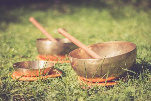 Set of metal singing bowls in the grass of the own garden, zen