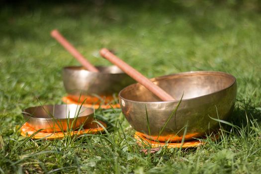 Set of metal singing bowls in the grass of the own garden, zen