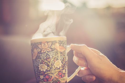 Steaming tea cup and sunlight, warm-up in winter