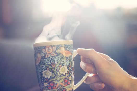 Steaming tea cup and sunlight, warm-up in winter