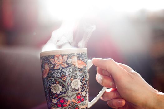 Steaming tea cup and sunlight, warm-up in winter