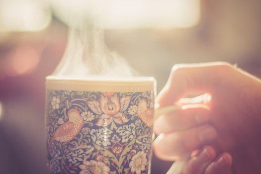 Steaming tea cup and sunlight, warm-up in winter