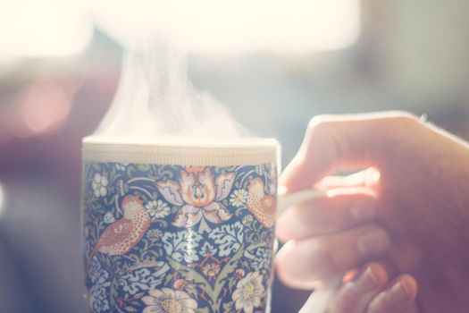 Steaming tea cup and sunlight, warm-up in winter