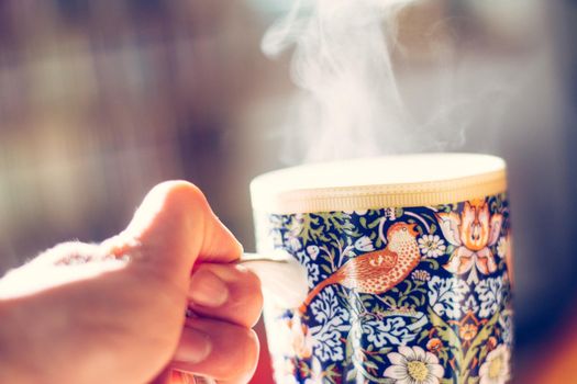 Steaming tea cup and sunlight, warm-up in winter