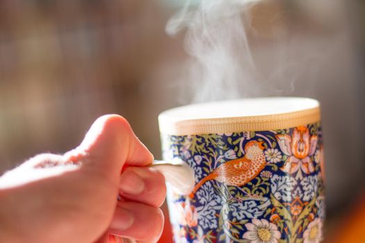 Steaming tea cup and sunlight, warm-up in winter