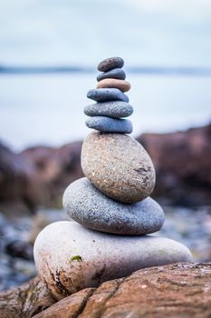 Close up picture of a stone cairn outdoors. Ocean in the blurry background