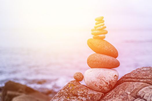 Close up picture of a stone cairn outdoors. Ocean in the blurry background. Sunshine.
