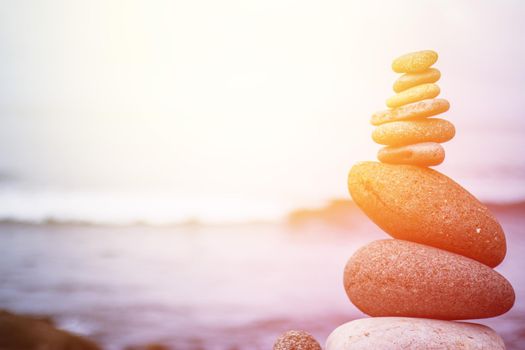 Close up picture of a stone cairn outdoors. Ocean in the blurry background. Sunshine.