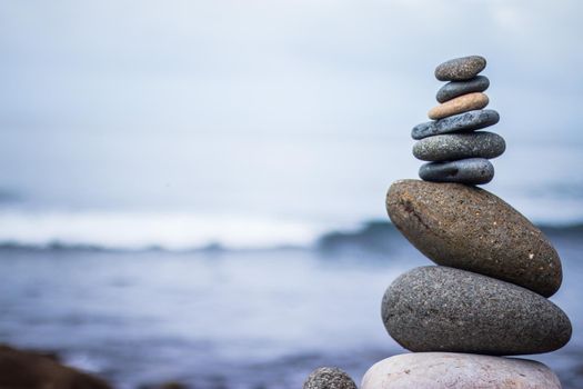Close up picture of a stone cairn outdoors. Ocean in the blurry background