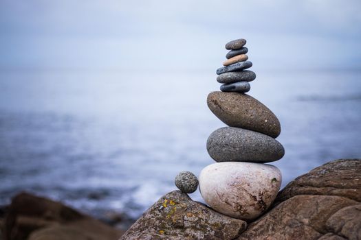 Close up picture of a stone cairn outdoors. Ocean in the blurry background