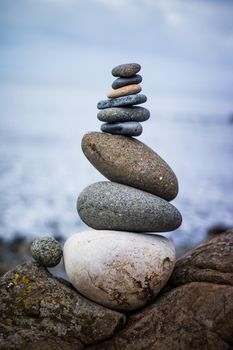 Close up picture of a stone cairn outdoors. Ocean in the blurry background