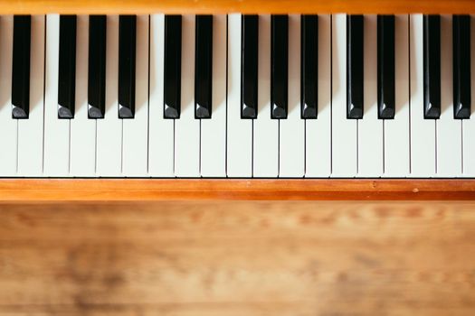 Vintage wooden piano. Keys in the foreground, wooden floor in the blurry background
