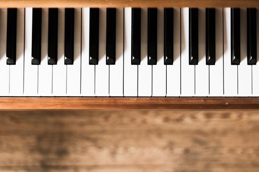 Vintage wooden piano. Keys in the foreground, wooden floor in the blurry background