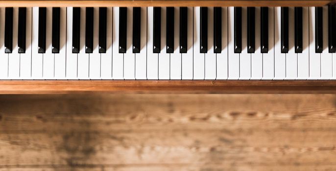 Vintage wooden piano. Keys in the foreground, wooden floor in the blurry background