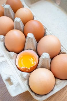 Closeup cracked brown eggs Arranged in a paper box Buy from the supermarket, put it on the wooden floor.