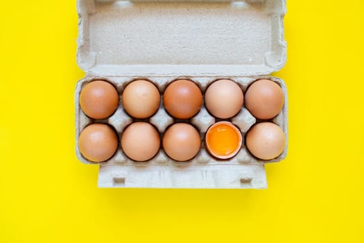 Closeup cracked brown eggs And eggs in paper boxes Placed side by side on a yellow background.