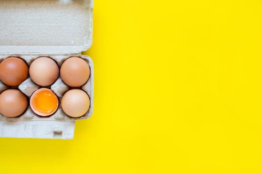 Closeup cracked brown eggs And eggs in paper boxes Placed side by side on a yellow background.