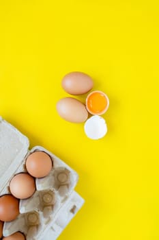 Closeup cracked brown eggs And eggs in paper boxes Placed side by side on a yellow background.