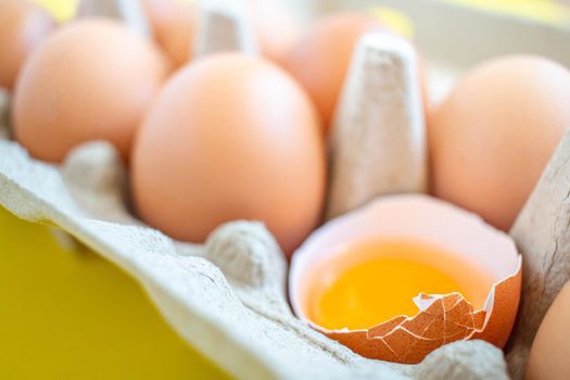 Closeup cracked brown eggs Arranged in a paper box Buy from supermarket Placed on a yellow background