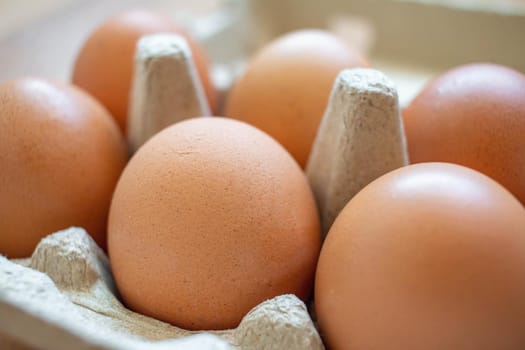 Closeup brown eggs in paper box There is not a full box of eggs. Buy from the supermarket, put it on the wooden floor.