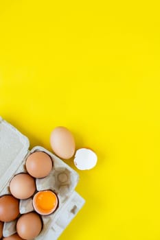 Closeup cracked brown eggs And eggs in paper boxes Placed side by side on a yellow background.