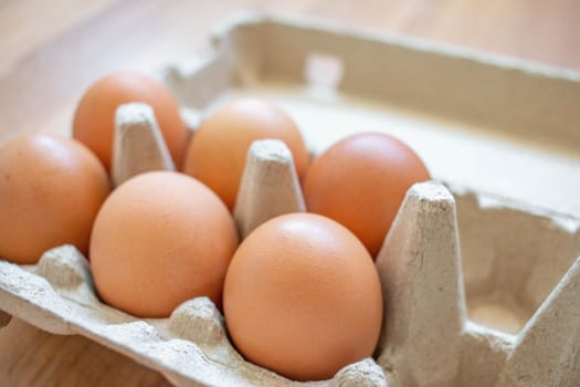 Closeup brown eggs in paper box There is not a full box of eggs. Buy from the supermarket, put it on the wooden floor.