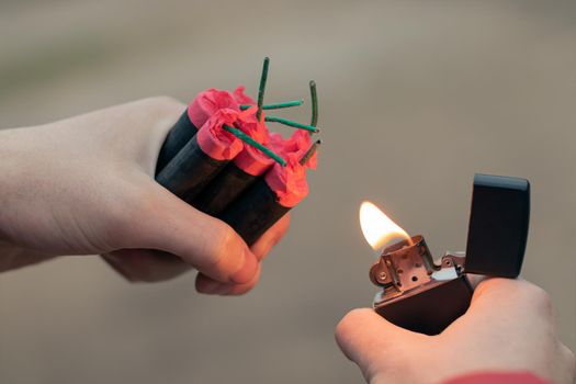 Man Lighting Up Several Firecrackers in his Hand Using Gasoline Lighter. Guy Getting Ready for New Year Fun with Fireworks or Pyrotechnic Products - CloseUp Shot, Rear View