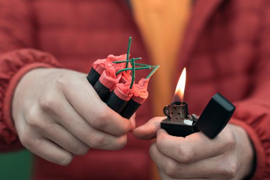 Man in Red Jacked Lighting Up Several Firecrackers in his Hand Using Gasoline Lighter. Guy Getting Ready for New Year Fun with Fireworks or Pyrotechnic Products